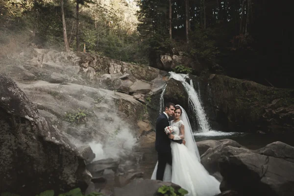 Bella coppia di sposi soggiorno sulla pietra del fiume in montagne panoramiche — Foto Stock