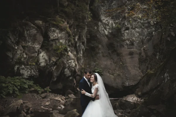 Hermosa pareja de boda estancia en piedra del río en las montañas escénicas — Foto de Stock