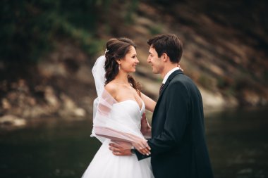 Zarif nazik şık damat ve gelin taşlarla Nehri yakınında. Evlilik çift aşık