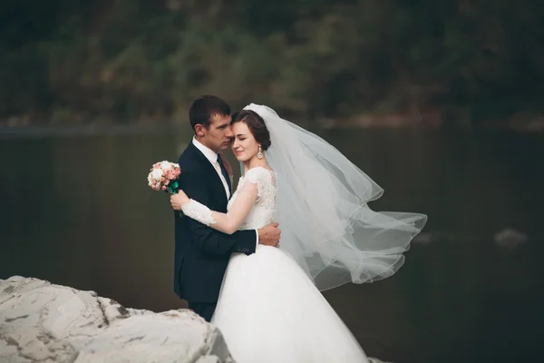 잘생긴 로맨틱 신랑과 포즈를 취하는 아름 다운 산에 강 근처 아름 다운 신부 — 스톡 사진