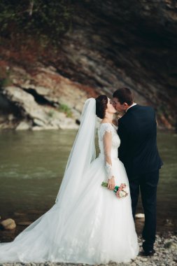 Yakışıklı romantik damat ve güzel gelin Nehri manzaralı dağlarında yakınında poz