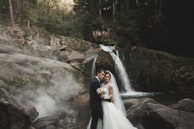 Güzel düğün çifti Nehri manzaralı dağlarda taş kalmak