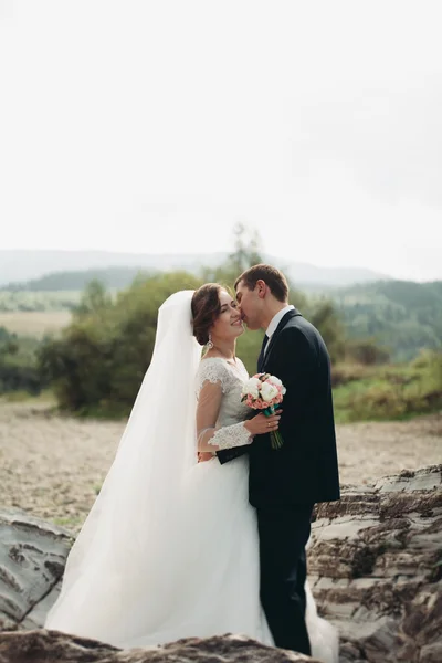 Όμορφος groom ρομαντική και όμορφη νύφη που παρουσιάζουν κοντά ποταμός στα γραφικά βουνά — Φωτογραφία Αρχείου