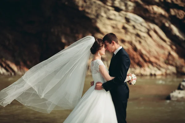 Bello sposo romantico e bella sposa in posa vicino al fiume in montagne panoramiche — Foto Stock
