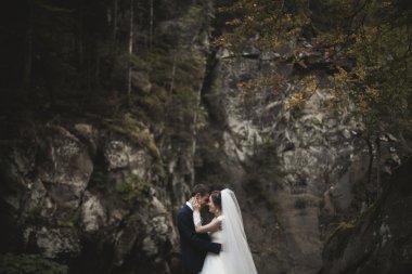 Güzel düğün çifti Nehri manzaralı dağlarda taş kalmak