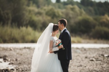Yakışıklı romantik damat ve güzel gelin Nehri manzaralı dağlarında yakınında poz