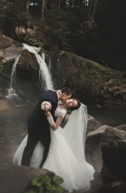 Güzel düğün çifti Nehri manzaralı dağlarda taş kalmak