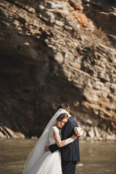 Красивый романтический жених и красивая невеста позируют у реки в живописных горах — стоковое фото