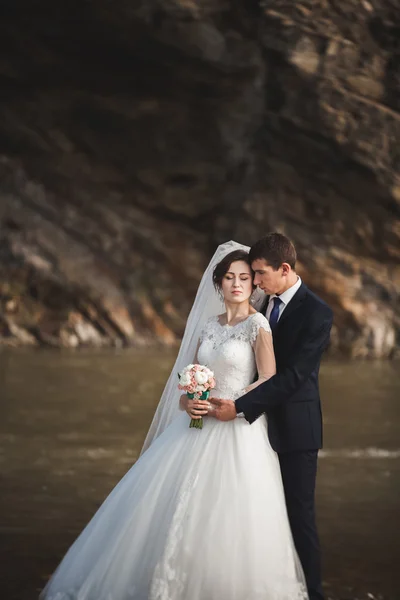 Beau marié romantique et belle mariée posant près de la rivière dans les montagnes pittoresques — Photo