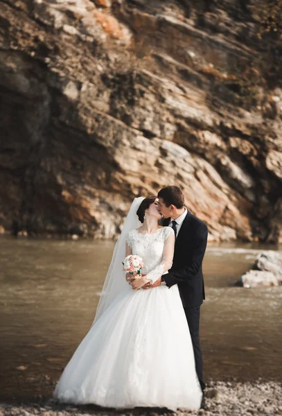 Beau marié romantique et belle mariée posant près de la rivière dans les montagnes pittoresques — Photo