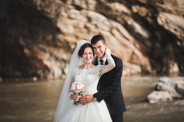 Schöner romantischer Bräutigam und schöne Braut posieren in Flussnähe in malerischen Bergen — Stockfoto