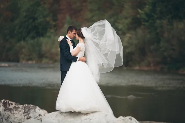 Schöner romantischer Bräutigam und schöne Braut posieren in Flussnähe in malerischen Bergen — Stockfoto