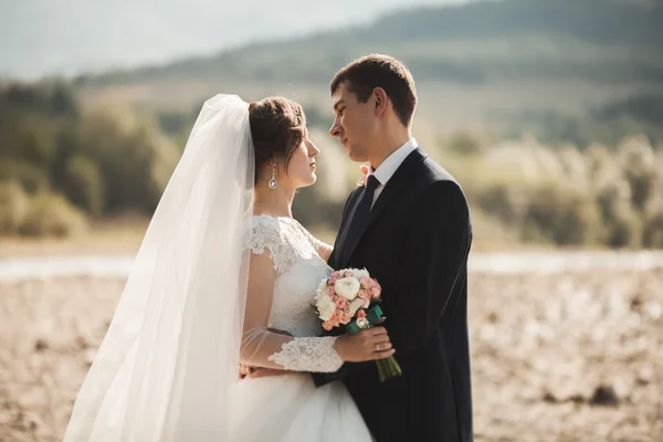 Beau marié romantique et belle mariée posant près de la rivière dans les montagnes pittoresques — Photo