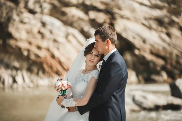 Beau marié romantique et belle mariée posant près de la rivière dans les montagnes pittoresques — Photo