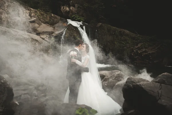 Beautiful wedding couple stay on stone of the river in scenic mountains — Stock Photo, Image