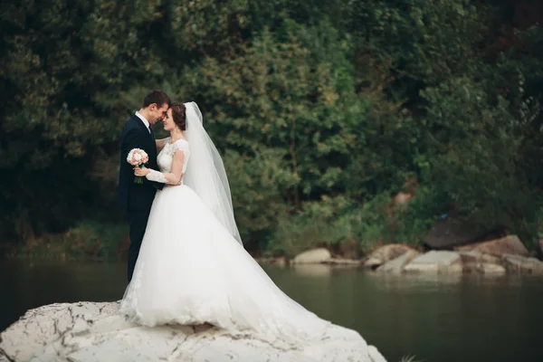 Vacker romantisk brudgummen och vackra brud poserar nära floden i natursköna berg — Stockfoto