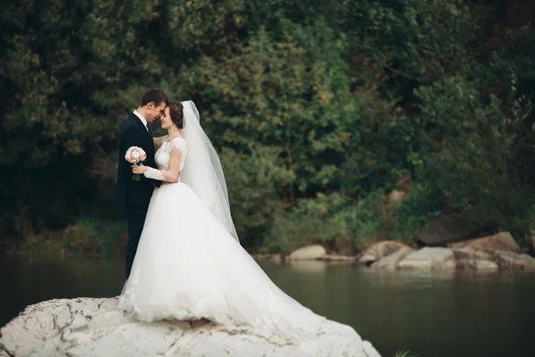 Knappe romantische bruid en bruidegom mooie poseren in de buurt van rivier in schilderachtige bergen — Stockfoto