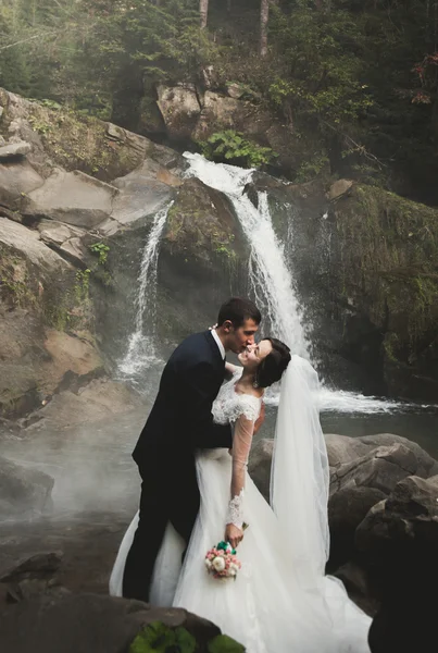 Casal bonito ficar na pedra do rio em montanhas cênicas — Fotografia de Stock