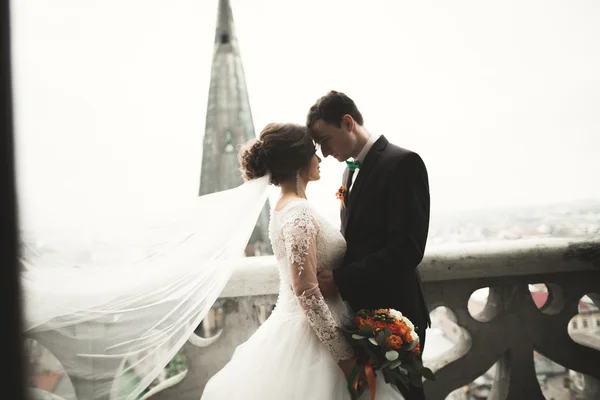 Hermosa pareja de recién casados de pie en el balcón con una vista de la ciudad — Foto de Stock