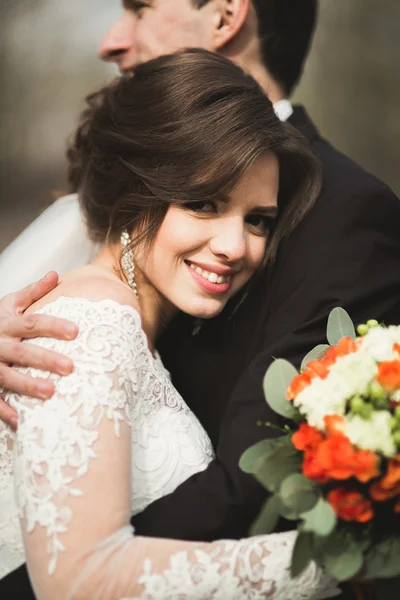 Casal elegante de recém-casados elegantes felizes andando no parque em seu dia de casamento com buquê — Fotografia de Stock