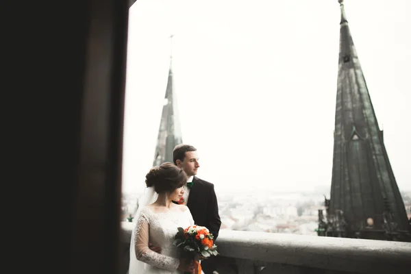 Hermosa pareja de recién casados de pie en el balcón con una vista de la ciudad — Foto de Stock