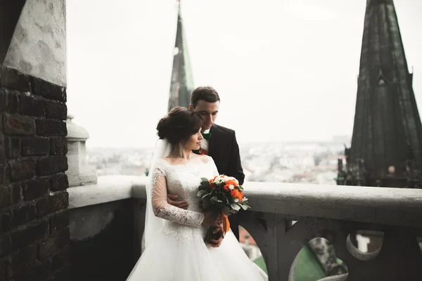 Hermosa pareja de recién casados de pie en el balcón con una vista de la ciudad —  Fotos de Stock