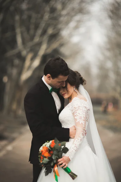 Beautiful happy wedding couple walking in the park on their day with bouquet — Stock Photo, Image