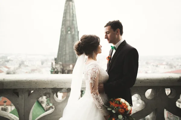 Hermosa pareja de recién casados de pie en el balcón con una vista de la ciudad —  Fotos de Stock