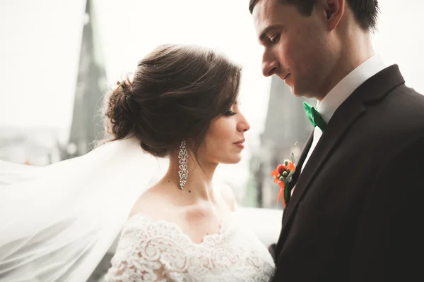 Hermosa pareja de recién casados de pie en el balcón con una vista de la ciudad — Foto de Stock