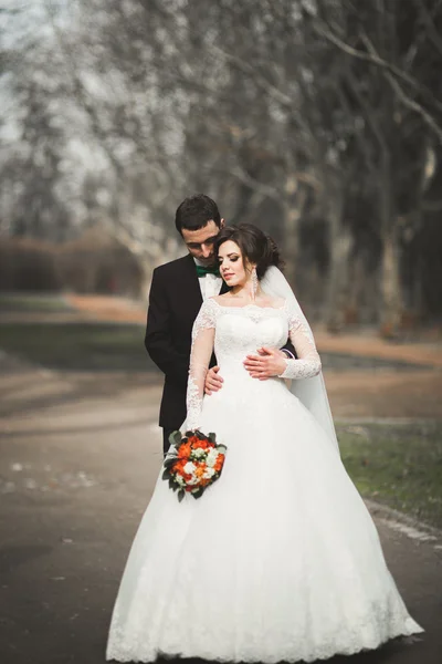 Beautiful happy wedding couple walking in the park on their day with bouquet — Stock Photo, Image