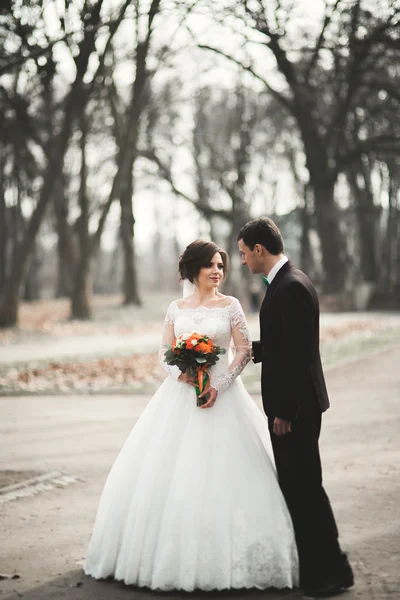 Beautiful happy wedding couple walking in the park on their day with bouquet — Stock Photo, Image