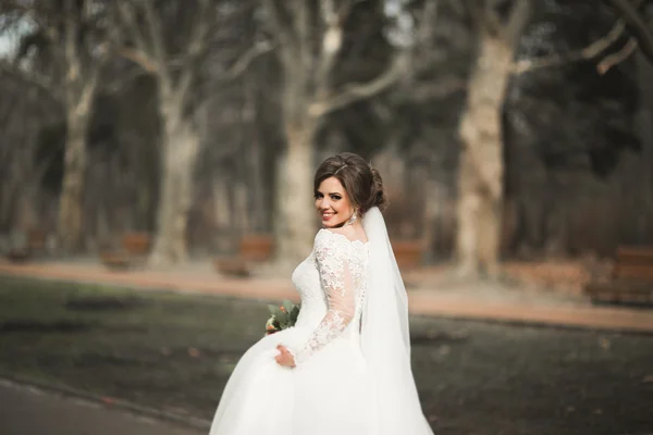 Krásná nevěsta v parku na její svatební den s kyticí — Stock fotografie