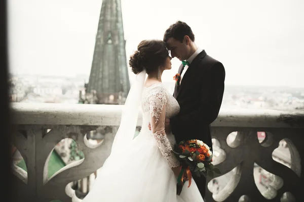 Piękny ślub para nowożeńców stojąc na balkonie z widokiem na miasto — Zdjęcie stockowe