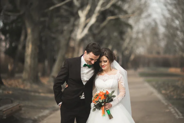 Krásné šťastné Svatební pár procházky v parku na jejich den s kyticí — Stock fotografie