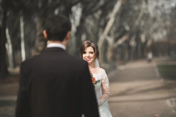 Beautiful happy wedding couple walking in the park on their day with bouquet — Stock Photo, Image