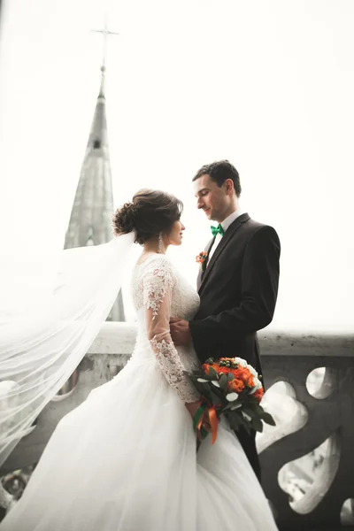 Красивая свадебная пара молодоженов, стоящих на балконе с видом на город — стоковое фото