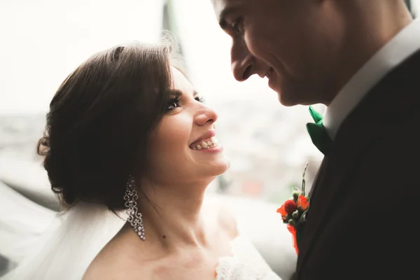 Hermosa pareja de recién casados de pie en el balcón con una vista de la ciudad — Foto de Stock