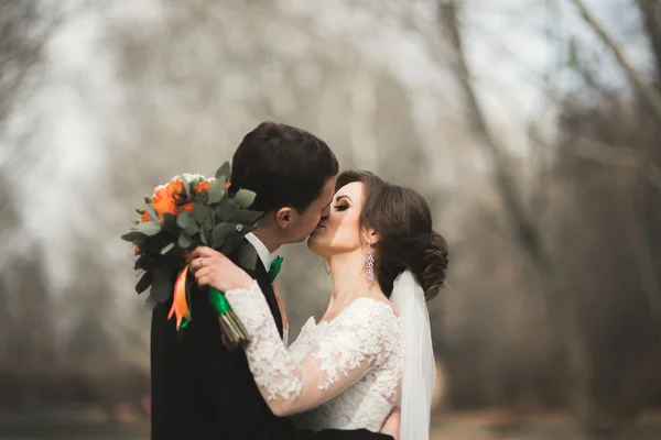 Beautiful happy wedding couple walking in the park on their day with bouquet — Stock Photo, Image