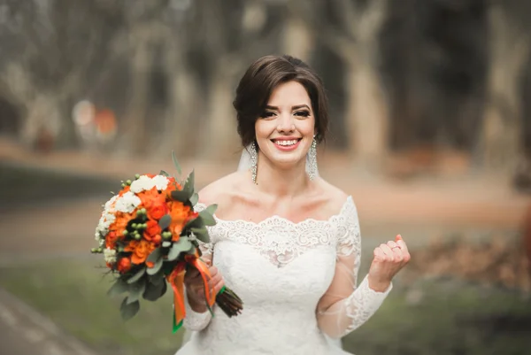 Schöne Braut im Park an ihrem Hochzeitstag mit Blumenstrauß — Stockfoto