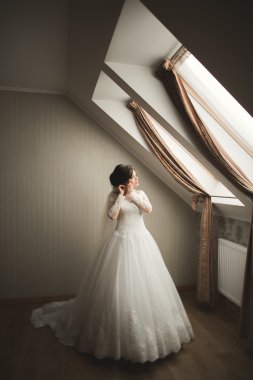 Beyaz elbiseli lüks gelin düğün törenine hazırlanırken poz veriyor.