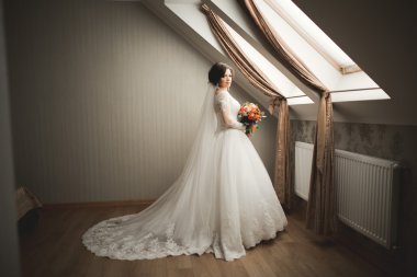 Beyaz elbiseli lüks gelin düğün törenine hazırlanırken poz veriyor.