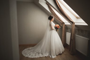 Beyaz elbiseli lüks gelin düğün törenine hazırlanırken poz veriyor.