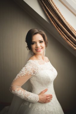 Beyaz elbiseli lüks gelin düğün törenine hazırlanırken poz veriyor.