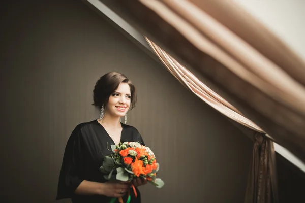 Noiva de luxo em roupão preto posando enquanto se prepara para a cerimônia de casamento — Fotografia de Stock