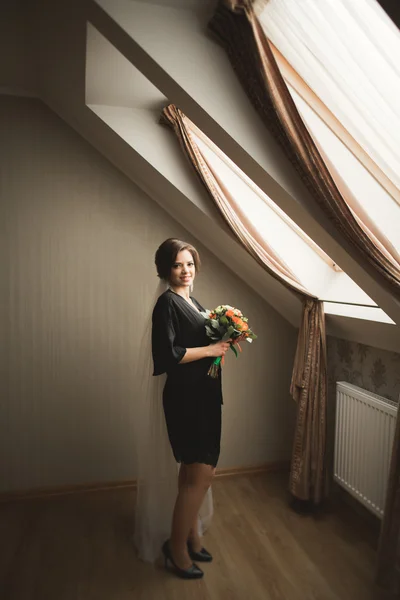 Роскошная невеста в черном халате позирует при подготовке к свадьбе — стоковое фото