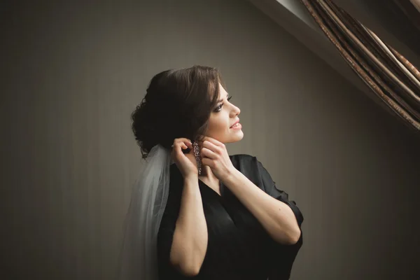 Noiva de luxo em roupão preto posando enquanto se prepara para a cerimônia de casamento — Fotografia de Stock