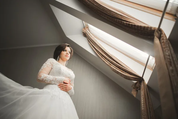 Роскошная невеста в белом платье позирует при подготовке к свадьбе — стоковое фото