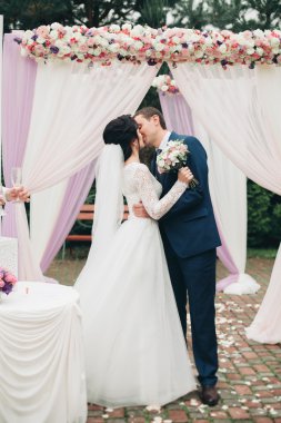 Çift ayakta taze çiçek bir kemerin altında düğün