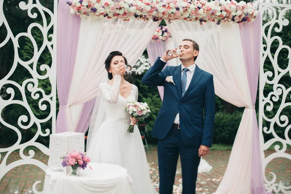 Свадебная пара, стоящая под сводом свежих цветов — стоковое фото