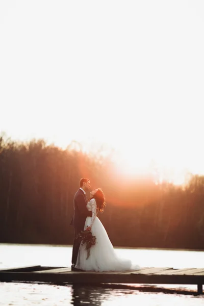 우아한 아름 다운 웨딩 커플 일몰에 호수 근처 포즈 — 스톡 사진